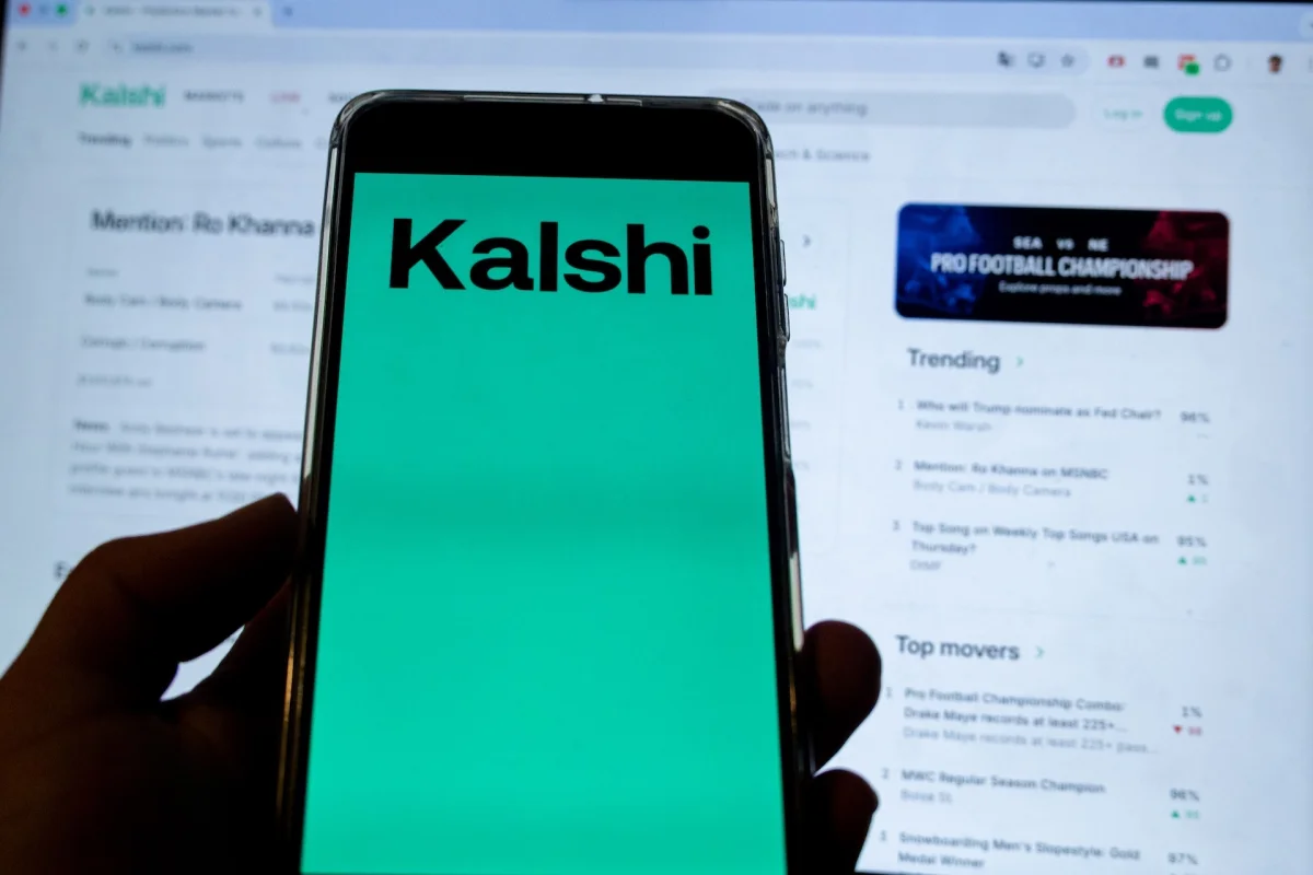Smartphone screen shows Kalshi logo.